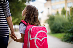 Mother holding child's hand on way to school