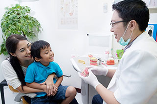 Pediatric dentist helping a child with autism feel comfortable during a dental visit